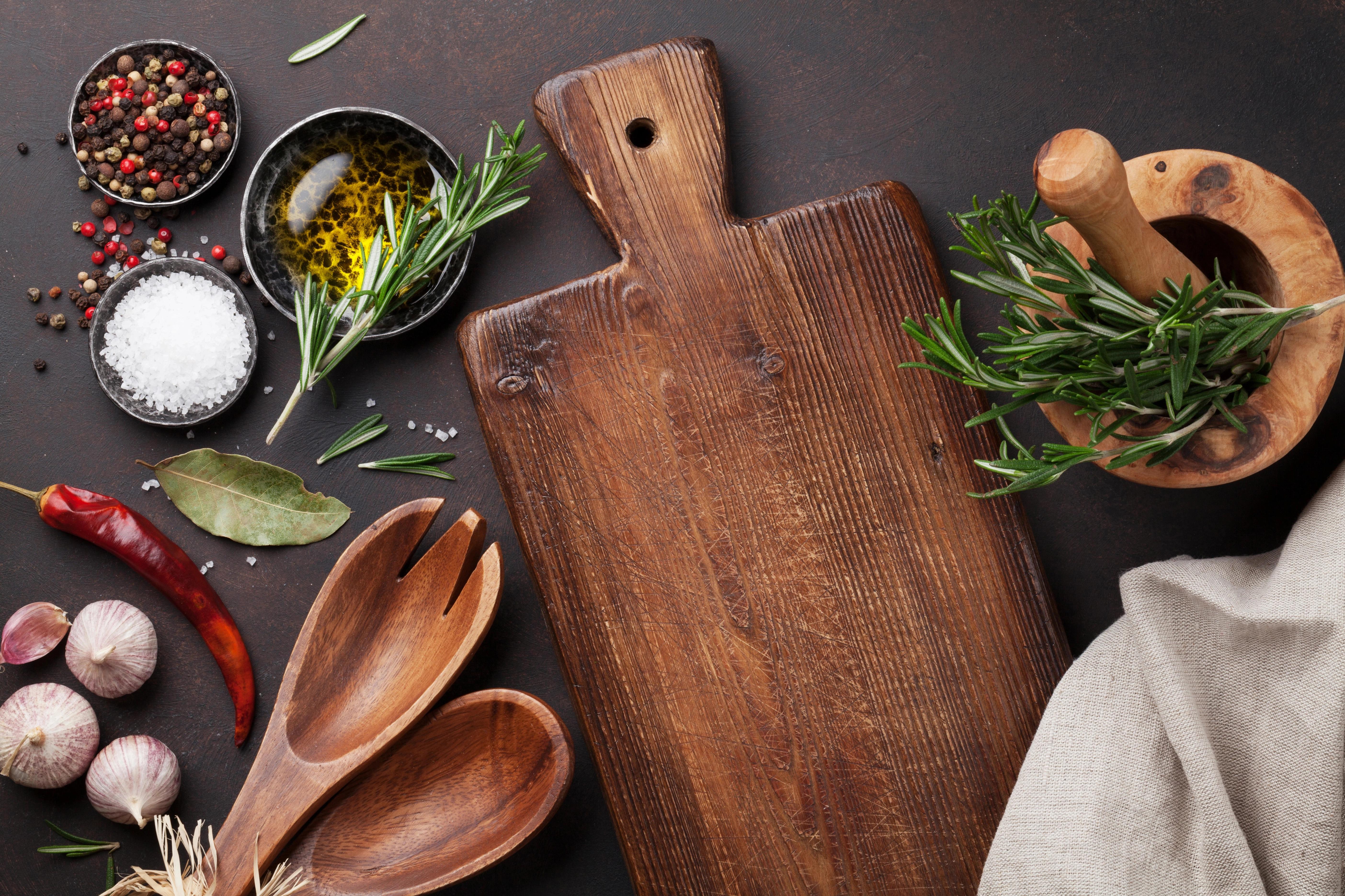 Prkénko obklopené zeleninou, kořením a miskami s ingrediencemi