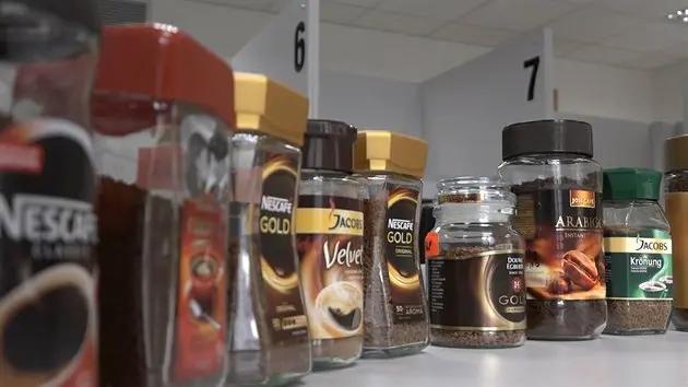 Lžička instantní kávy nad hrnkem s horkou vodou