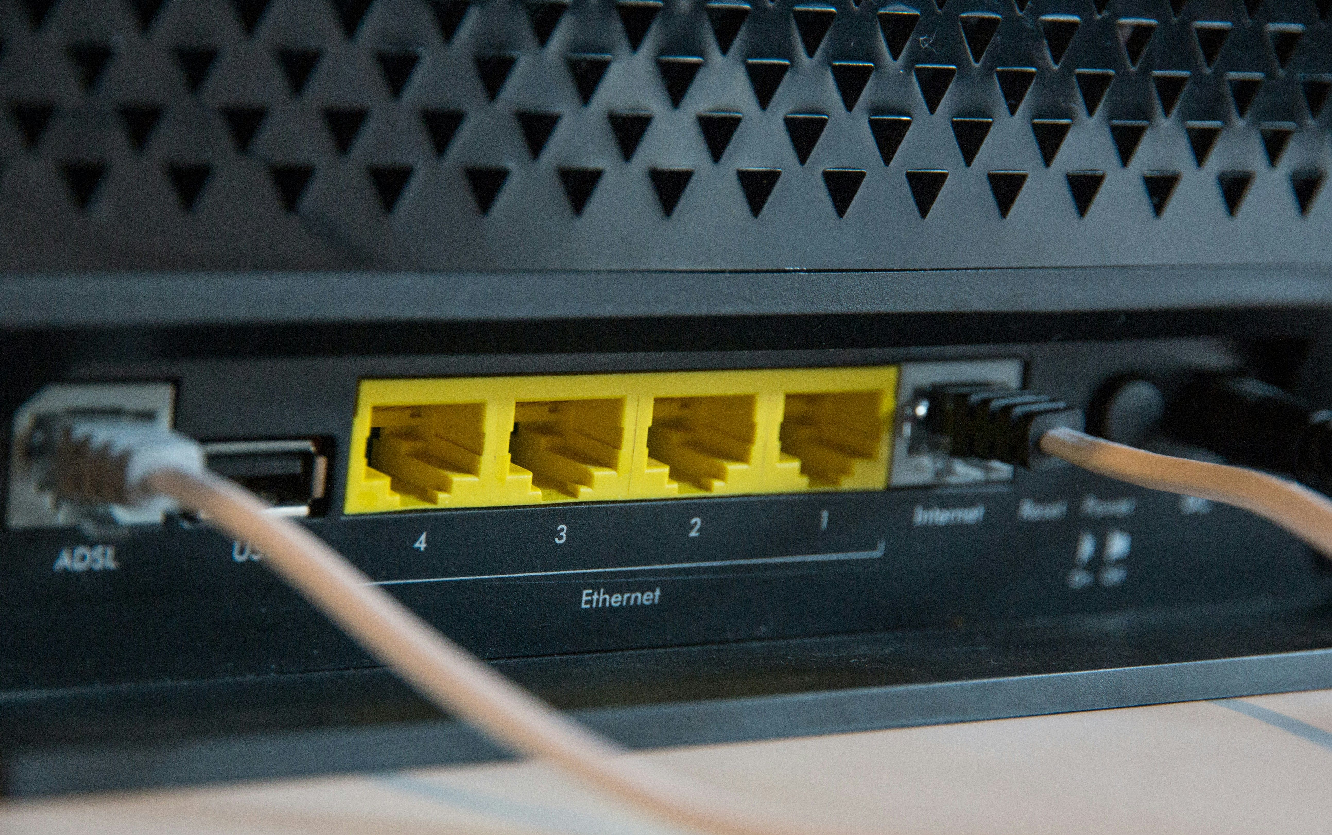 Detailní záběr na zadní stranu internetového modemu s ethernetovými porty a připojenými kabely