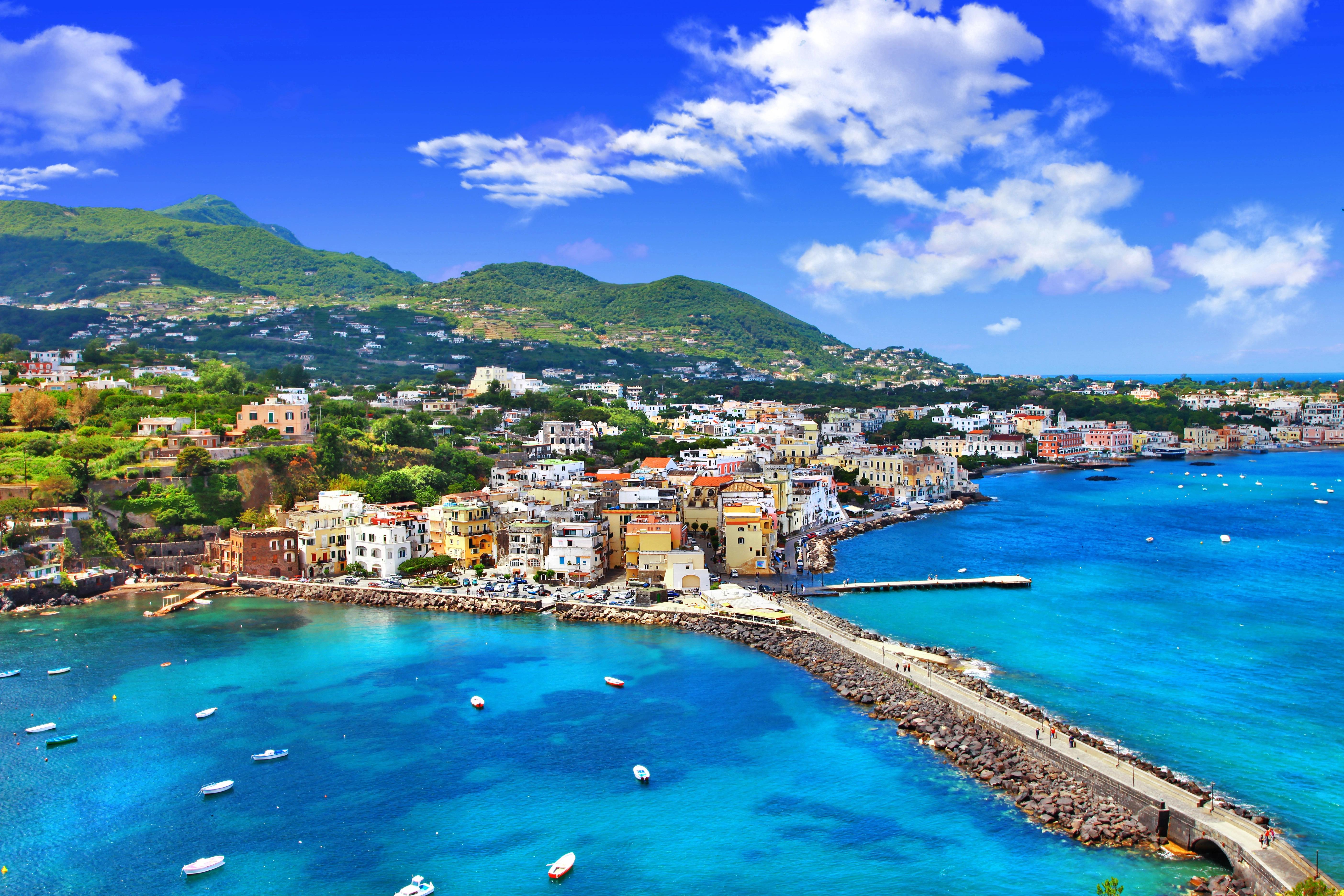 Panoramatický pohled na italský ostrov Ischia s mořem, městem a zelenými kopci v pozadí