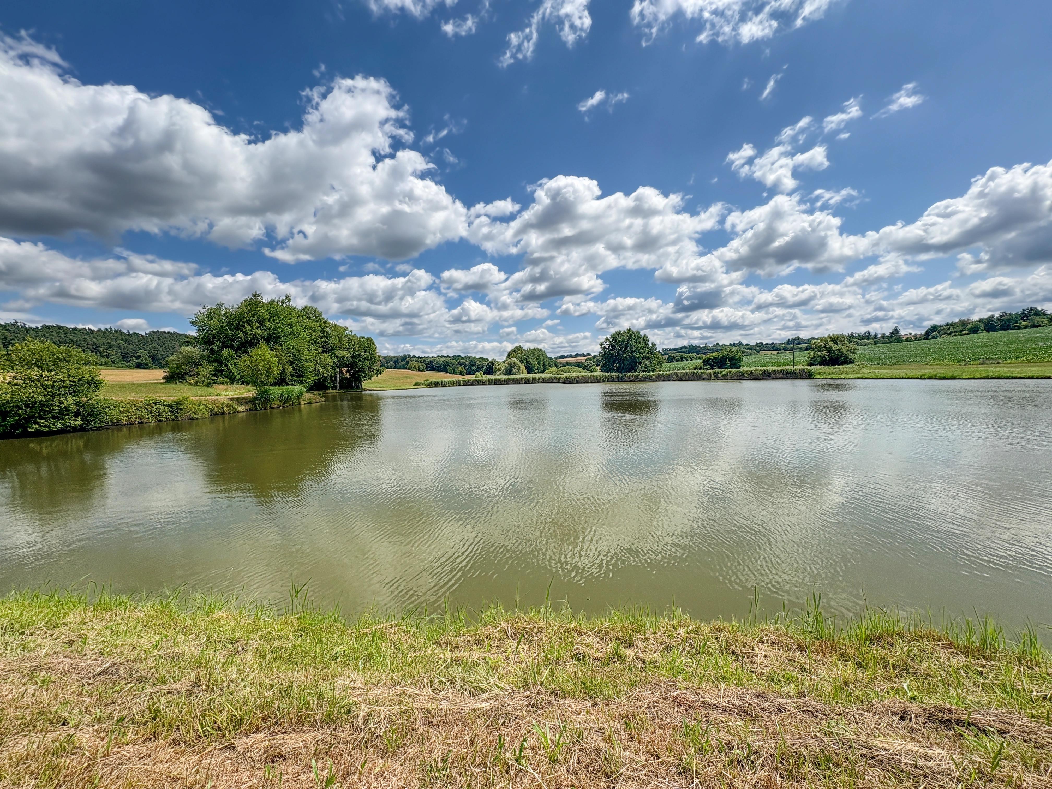 Letní jezero s odrazem oblak na hladině.