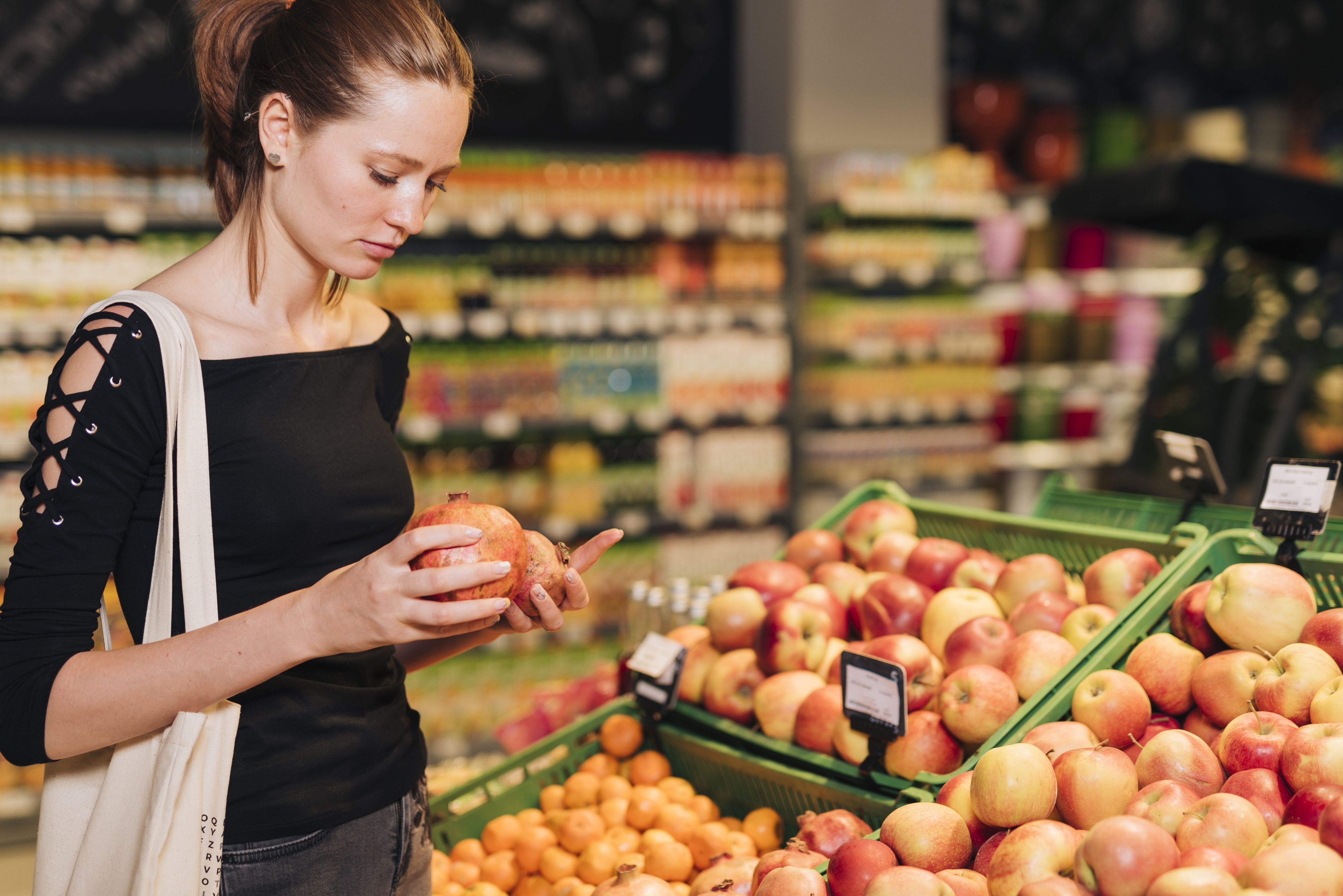 Ovoce vystavené v supermarketu s lidmi vybírajícími nejlepší kousky