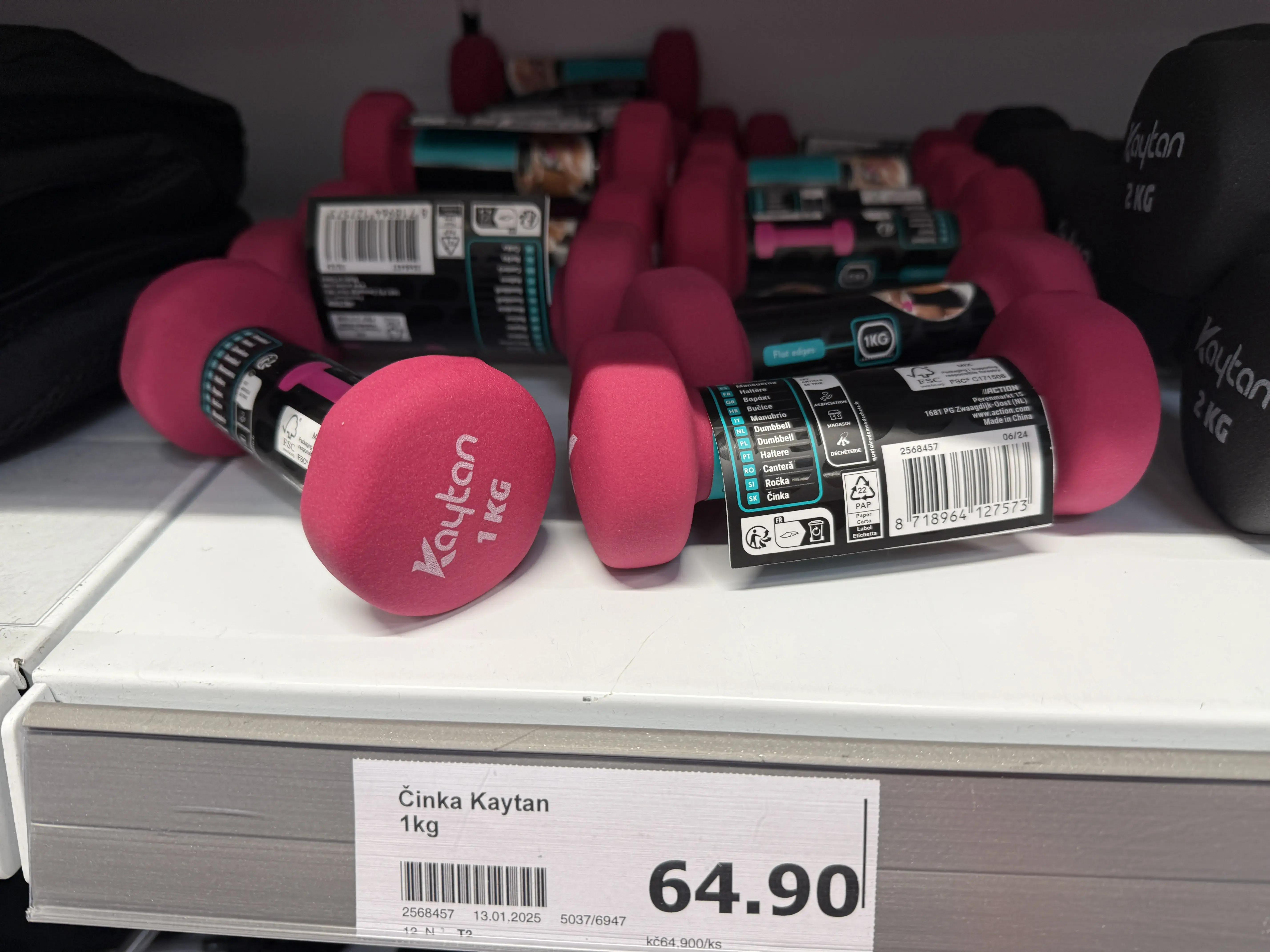 Činky různých hmotností vyskládané na regálu