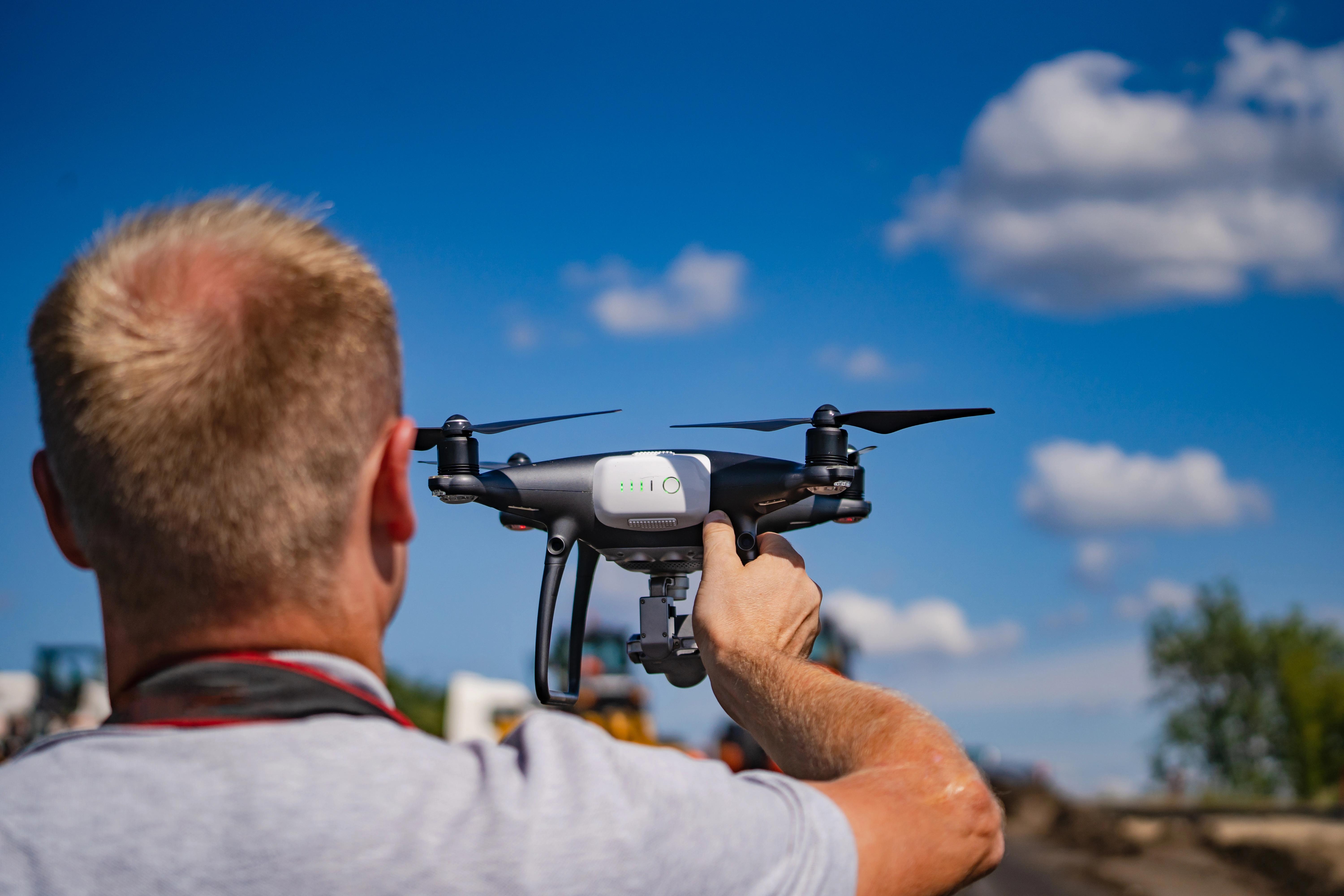Technik v reflexní vestě s tabletem a dronem před solárními panely.