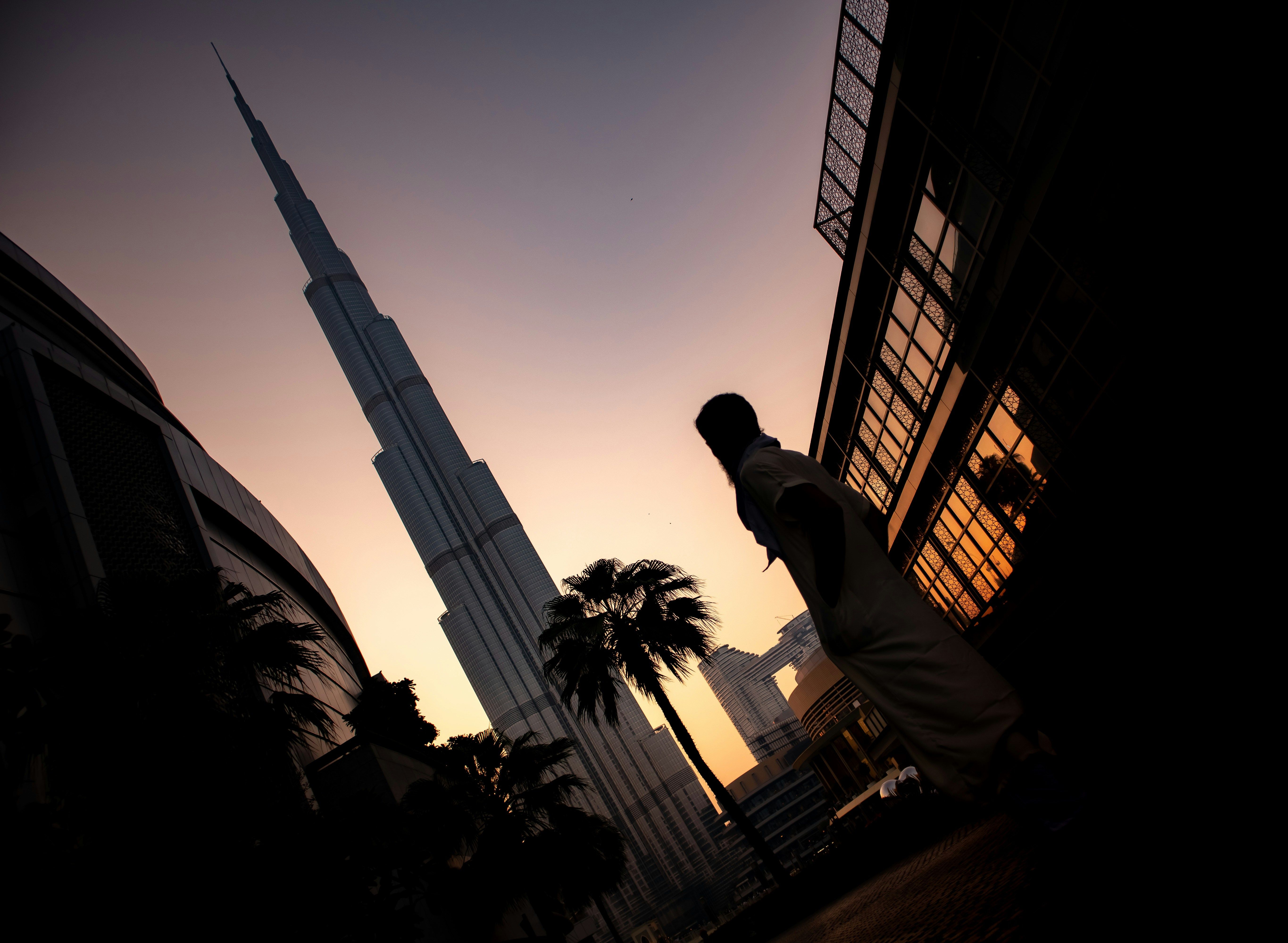 Osoba stojící poblíž Burj Khalifa během západu slunce v Dubaji, Spojené arabské emiráty