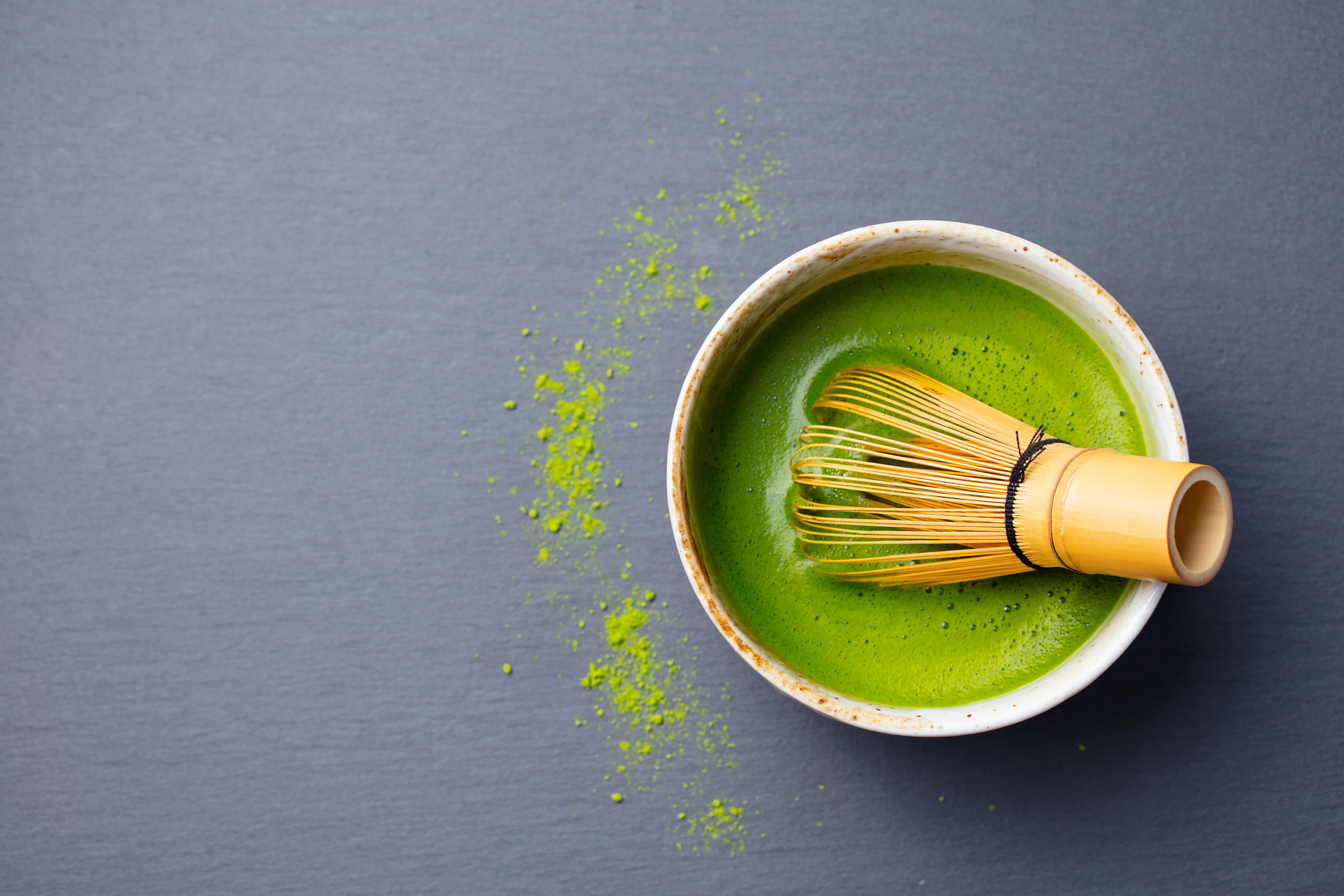 Šálek matcha čaje se svěží pěnou a bambusová metlička