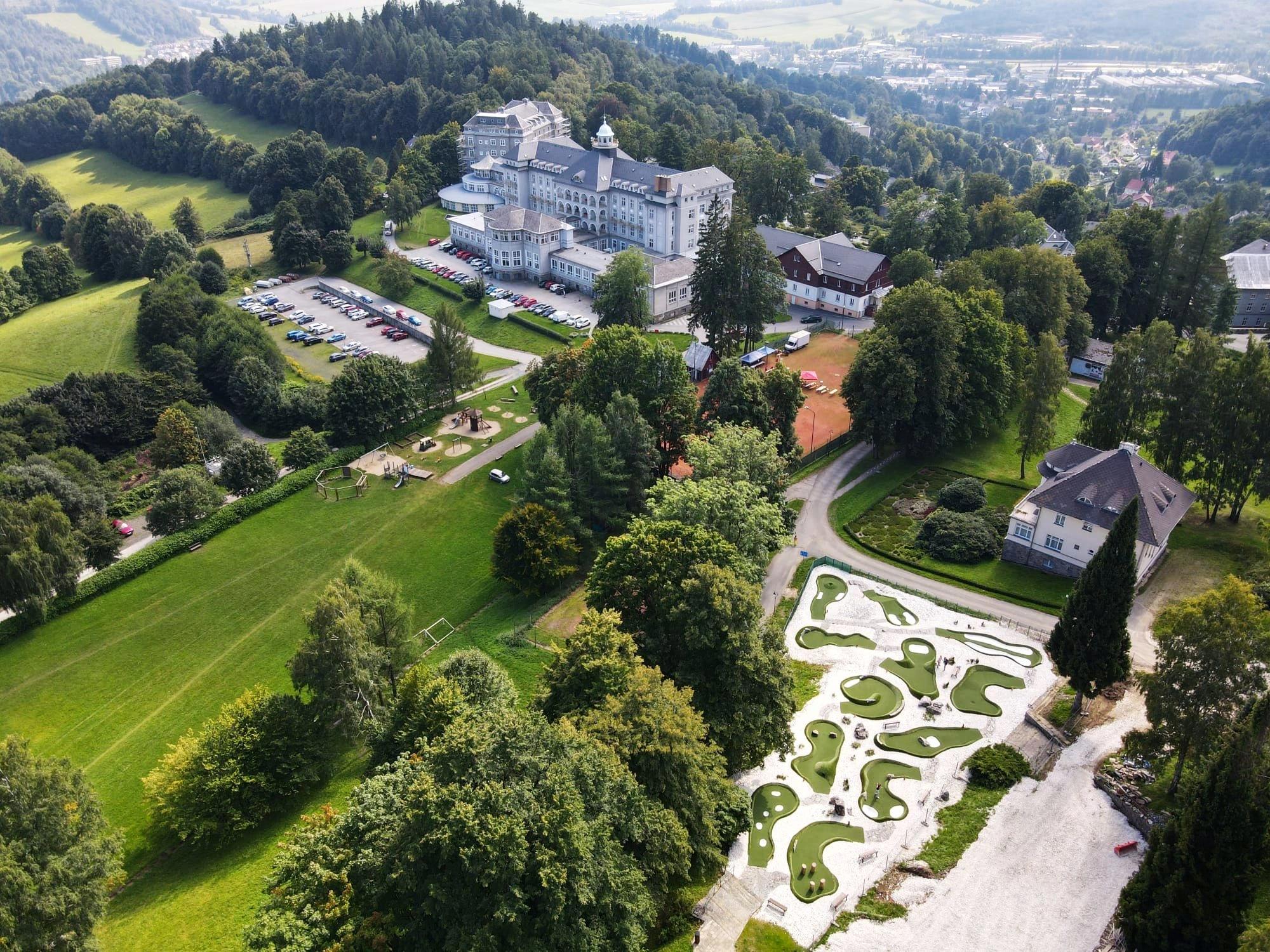 Monumentální schodiště vedoucí k hlavnímu vchodu do lázní, obklopené zelení