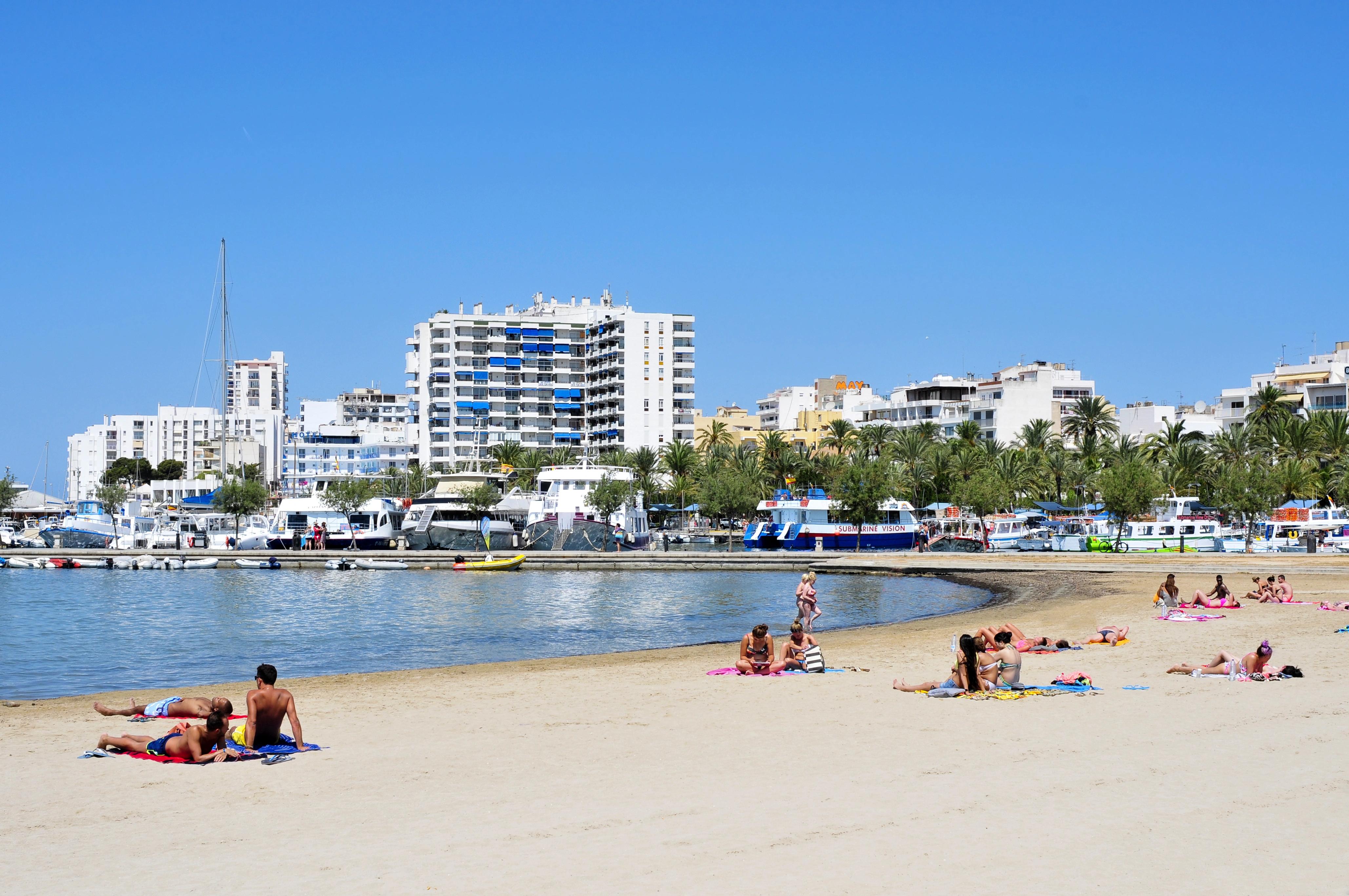 Turisté odpočívající na pláži před hotelovým komplexem
