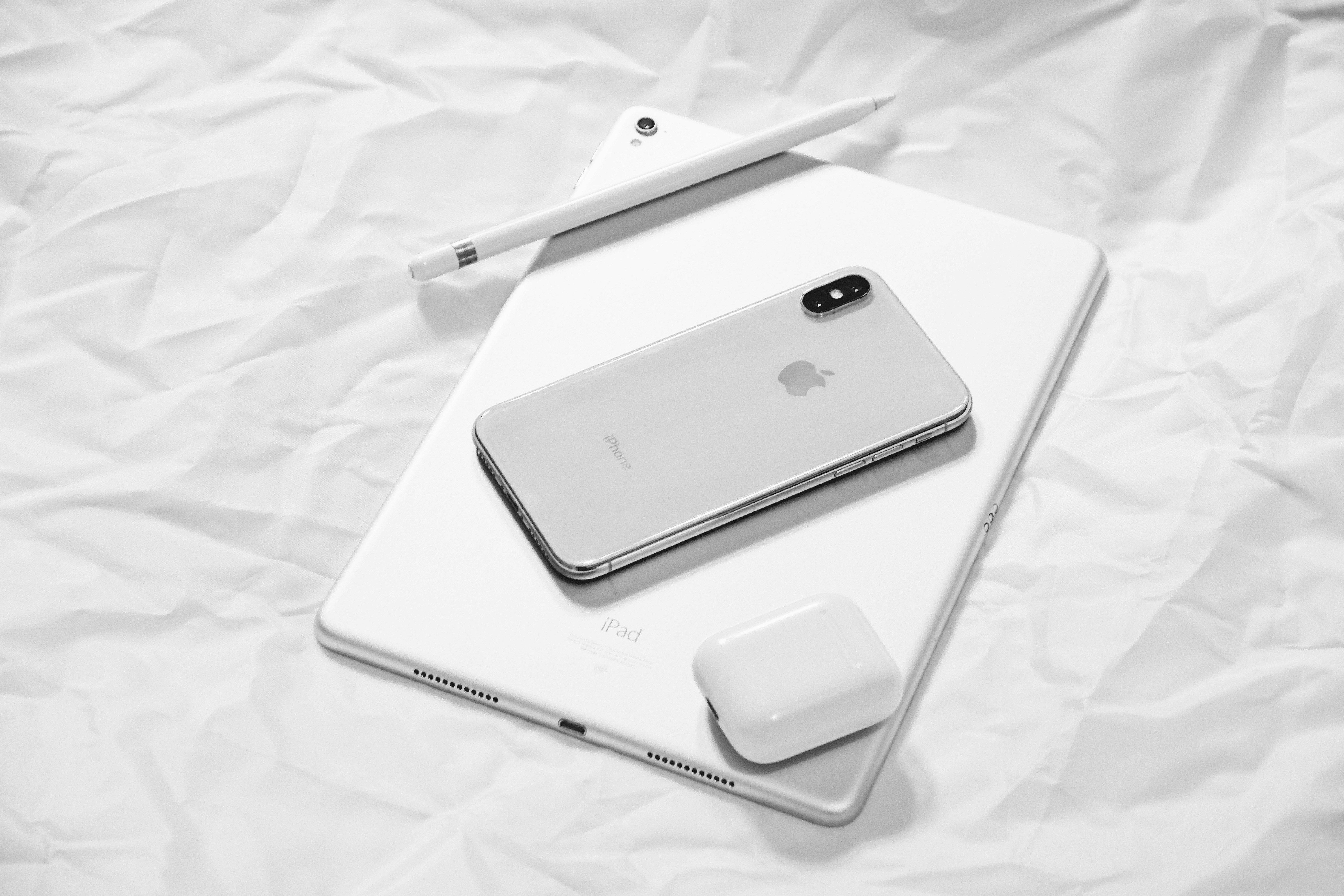 iPhone, iPad, AirPods a Apple Pencil na světlém pozadí.