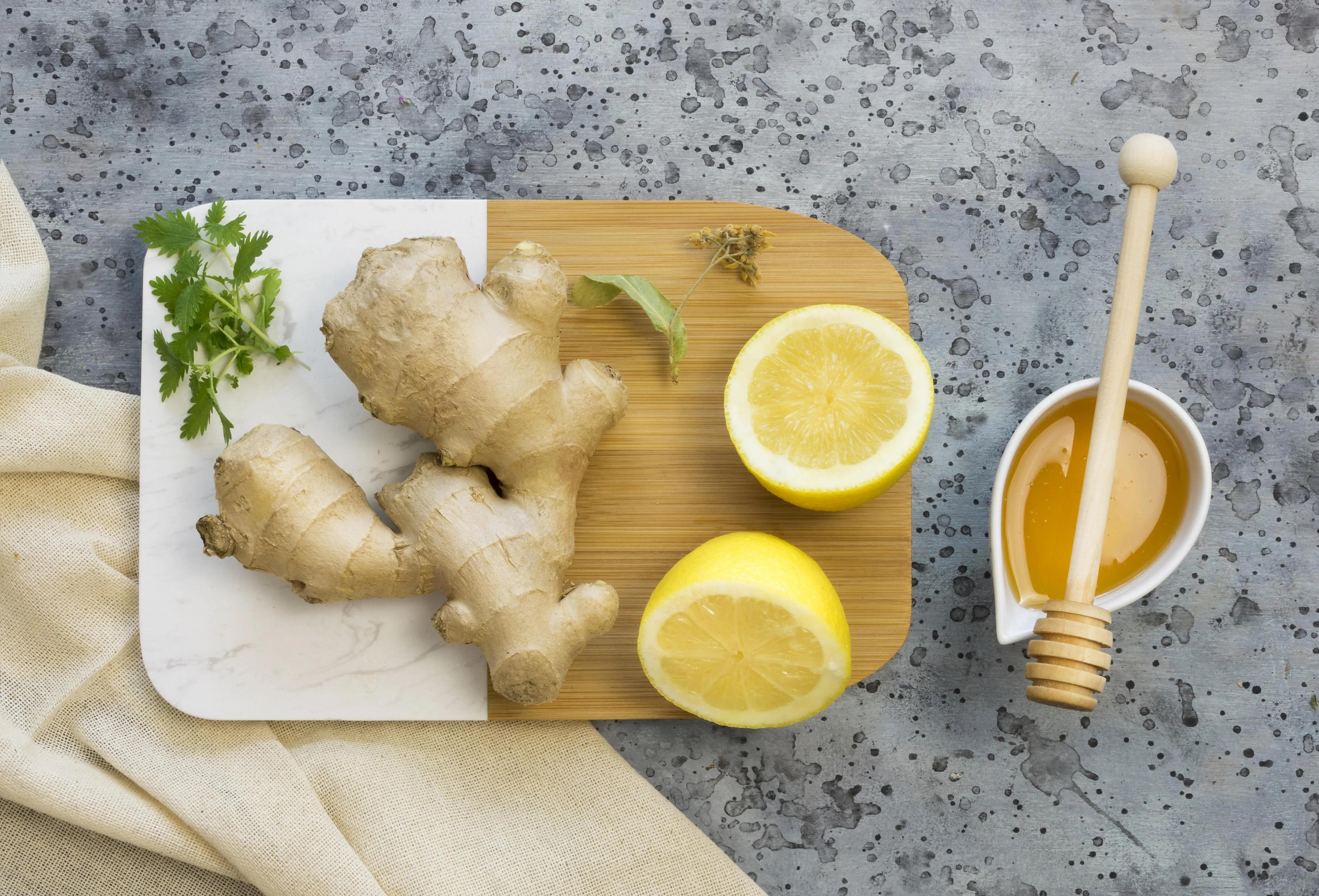 Kořen zázvoru nakrájený na plátky vedle medu a citronu
