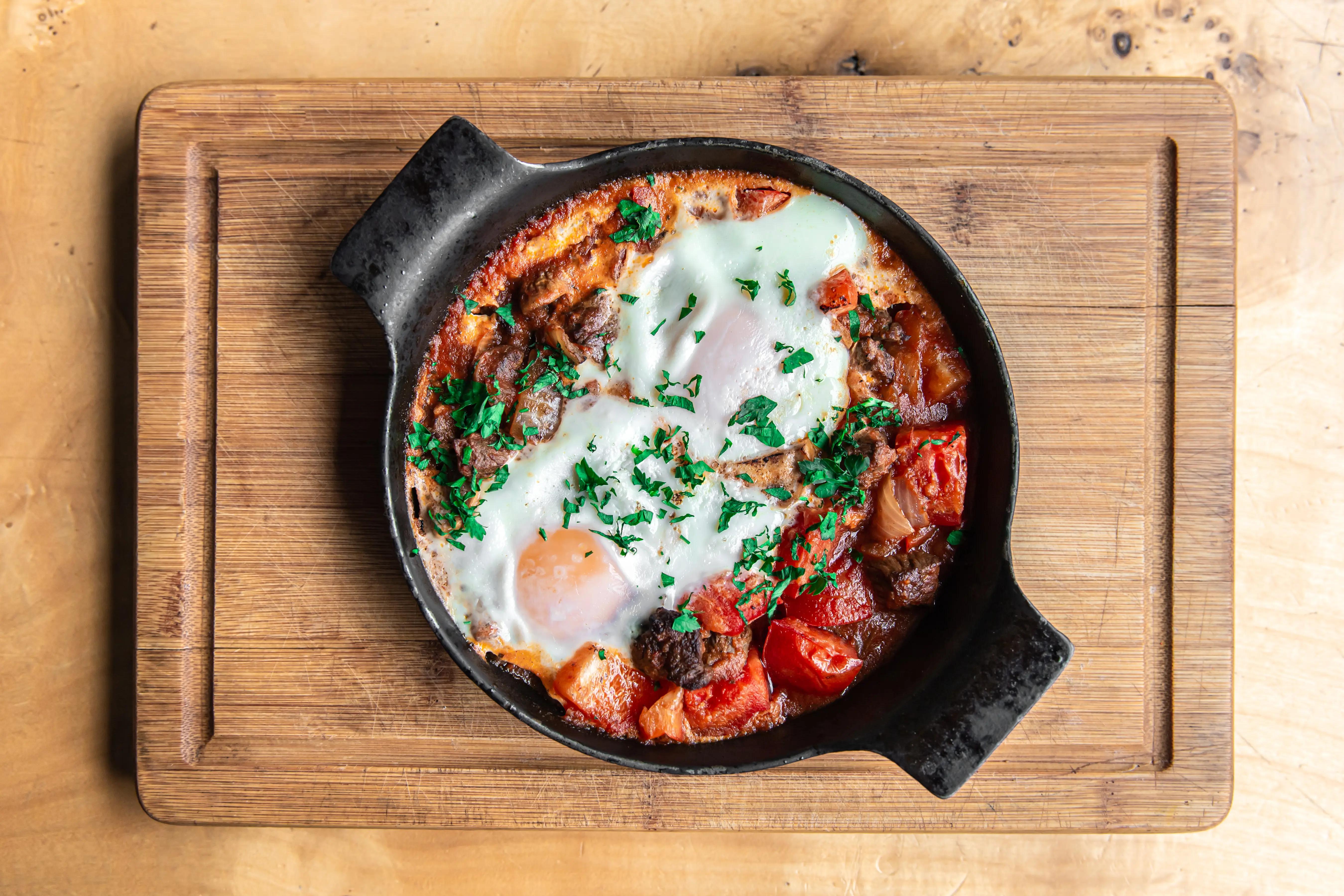 Čerstvě připravená shakshuka v pánvi s vejci a rajčatovou omáčkou